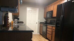 A kitchen with wooden cabinets, a black refrigerator, a microwave, and a stove.