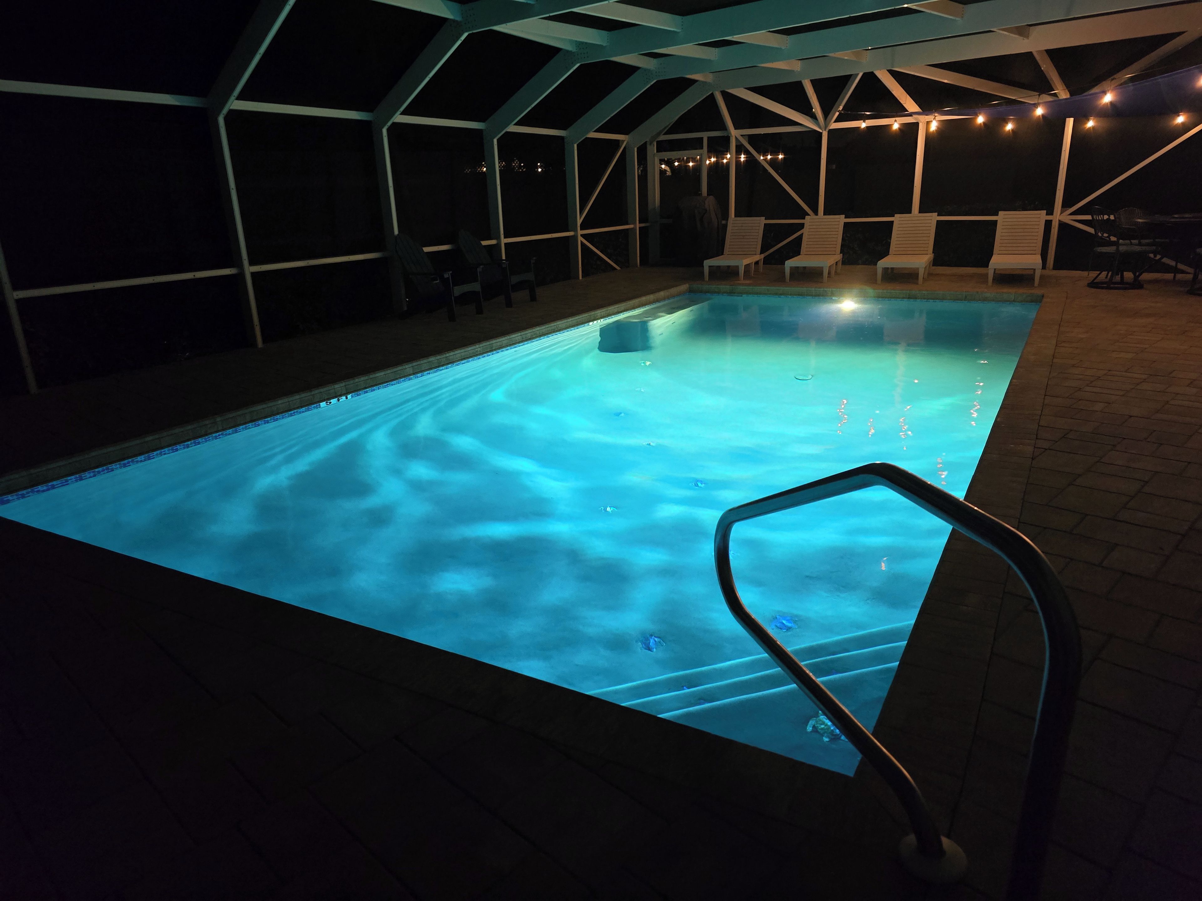 En inomhuspool med klart vatten, omgiven av solstolar och ett avskärmat sittområde.