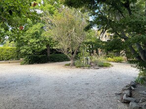 Un sendero de grava que atraviesa un jardín con diversos árboles y arbustos.