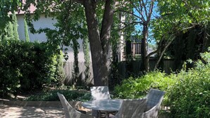 Une terrasse extérieure avec une table et quatre chaises, entourée d’arbres et d’une clôture en bois.