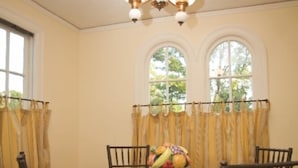 A dining room with a round glass table, six chairs, and a chandelier.