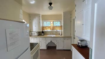 Una cocina con armarios blancos, microondas, cafetera y tostadora.