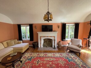 Un salón con chimenea, sofá, sillón y una alfombra estampada.