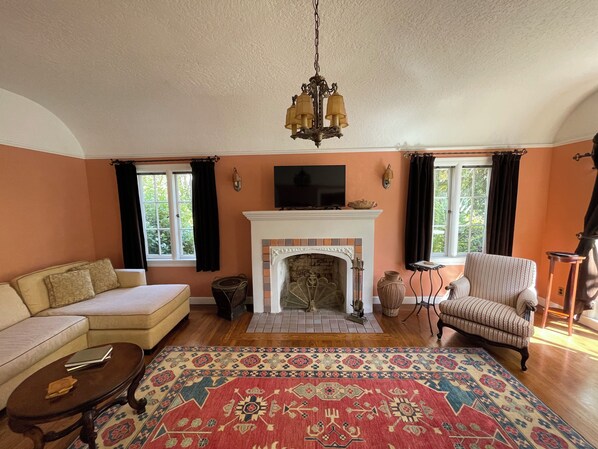 Un salón con chimenea, sofá, sillón y una alfombra estampada.
