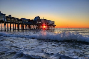 A pier with buildings extending over the water at sunset.