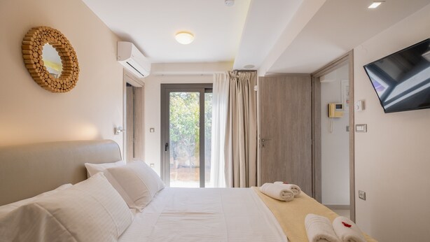 Ein Hotelzimmer mit Bett, Fernseher, Spiegel und Blick ins Freie.