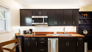 Una cocina moderna con armarios oscuros, electrodomésticos de acero inoxidable y encimera de madera.