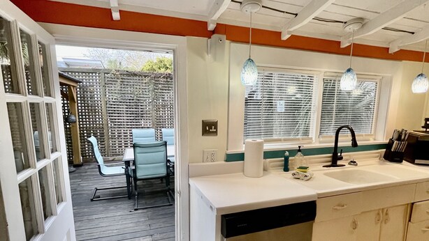 A kitchen with a dishwasher, sink, and a dining area with chairs and a table. - Lighthouse Cottage--1.5 blocks from beach.  (Tybee Island)