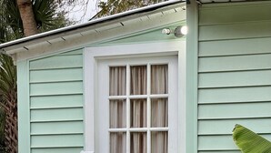 A small, single-story building with a green exterior and a white door. A sign above the door reads "LIGHTHOUSE COTTAGE 912 (912) 398-7011." - Lighthouse Cottage--1.5 blocks from beach.  (Tybee Island)