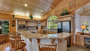 A spacious kitchen with wooden cabinets, granite countertops, and a central island with bar stools. - At Home in the Mountains , 7 bdrms 5 baths, Hot tub, Sauna, Steam rm & more (South Lake Tahoe)