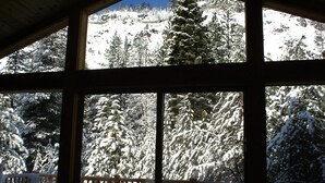 A cabin with large windows overlooking a snowy forest and mountains. - At Home in the Mountains , 7 bdrms 5 baths, Hot tub, Sauna, Steam rm & more (South Lake Tahoe)