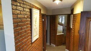 A hallway with a brick wall, a framed picture, and a wooden door. - COZY 2 BEDROOM OCEAN VIEW las gaviotas  17#2 (rosarito beach)
