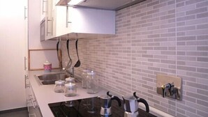 A kitchen with white cabinets, a stainless steel range hood, a tiled backsplash, and a black stovetop. - Fontana di Trevi and Spanish Steps. Modern and elegant (Roma)