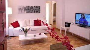 A modern living room with a white sofa, red cushions, a coffee table, and a television. - Fontana di Trevi and Spanish Steps. Modern and elegant (Roma)