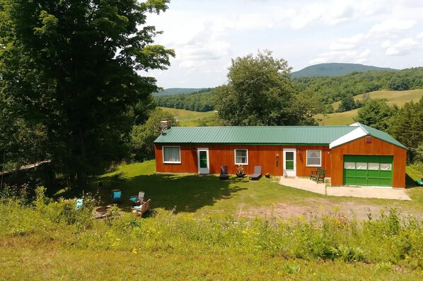 A rustic wooden house with a green roof, a garage, and a lawn with outdoor seating. - Mountain Top Retreat, 116 private acres (Hobart)