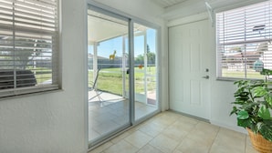 A room with a sliding glass door leading to a patio, a white door, and a potted plant.
