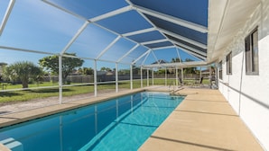 A swimming pool with a covered area and a house in the background.