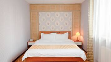 A hotel room with a bed, a nightstand, a lamp, and a patterned carpet.