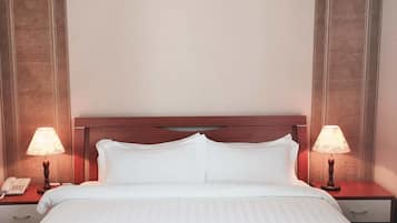 Una habitación de hotel con una cama, dos mesitas de noche, un teléfono y dos lámparas.