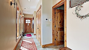 A hallway with wooden doors, a red patterned rug, and a bench.