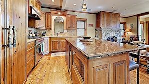 A spacious kitchen with wooden cabinets, a large island, and a stone backsplash.
