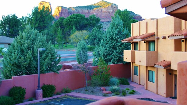 Un hotel con patio interior, rodeado de árboles y una montaña al fondo.