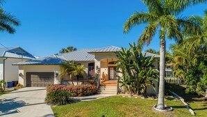 A residential house with a garage, a front porch, and a well-maintained lawn. - IMPERIAL PARADISE Naples, SFH, HEATED/CAGE pool, Near Beaches, discounts avail (Bonita Springs)