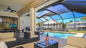 An outdoor lounge area with wicker furniture, a pool, and a ceiling fan. - IMPERIAL PARADISE Naples, SFH, HEATED/CAGE pool, Near Beaches, discounts avail (Bonita Springs)