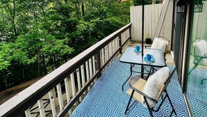 A balcony with a patterned floor, a table with chairs, and a large umbrella.