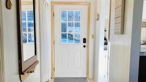 A hallway with a wooden door, a mirror, and a mat at the entrance.