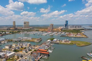 A marina with boats docked, a large building with a flat roof, and a smaller building with a sloped roof.