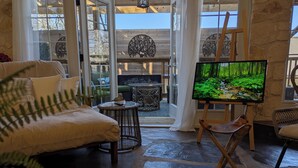 Een gezellige woonkamer met een grote flatscreen televisie, een comfortabele bank en een rieten salontafel.