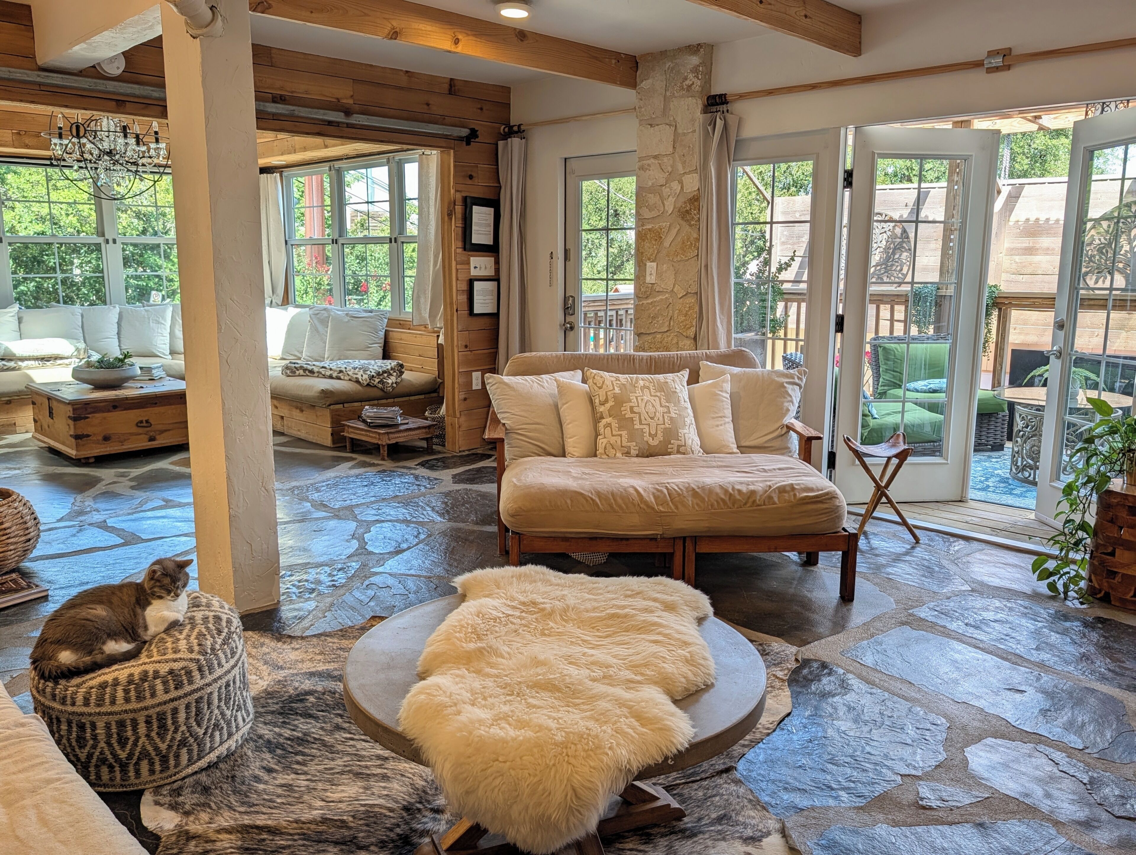 A cozy interior with a stone floor, a sofa, a chair, and a cat resting on a cushion.