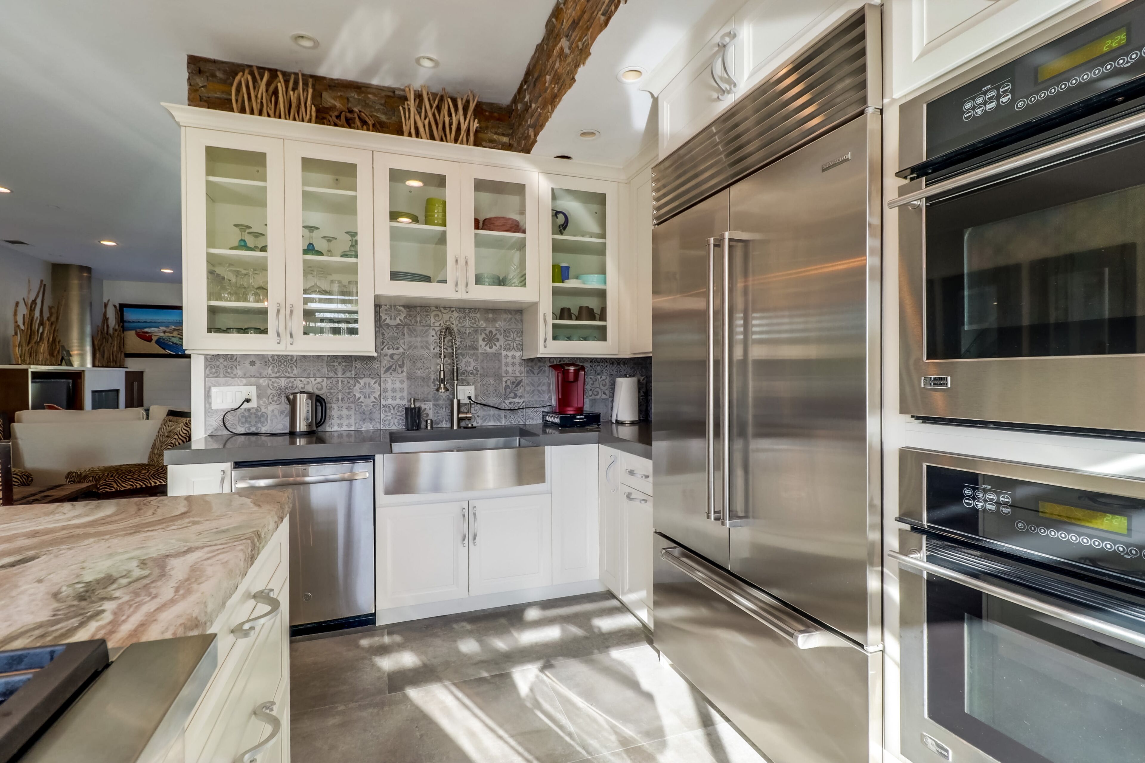 A modern kitchen with stainless steel appliances, white cabinetry, and a stone countertop.