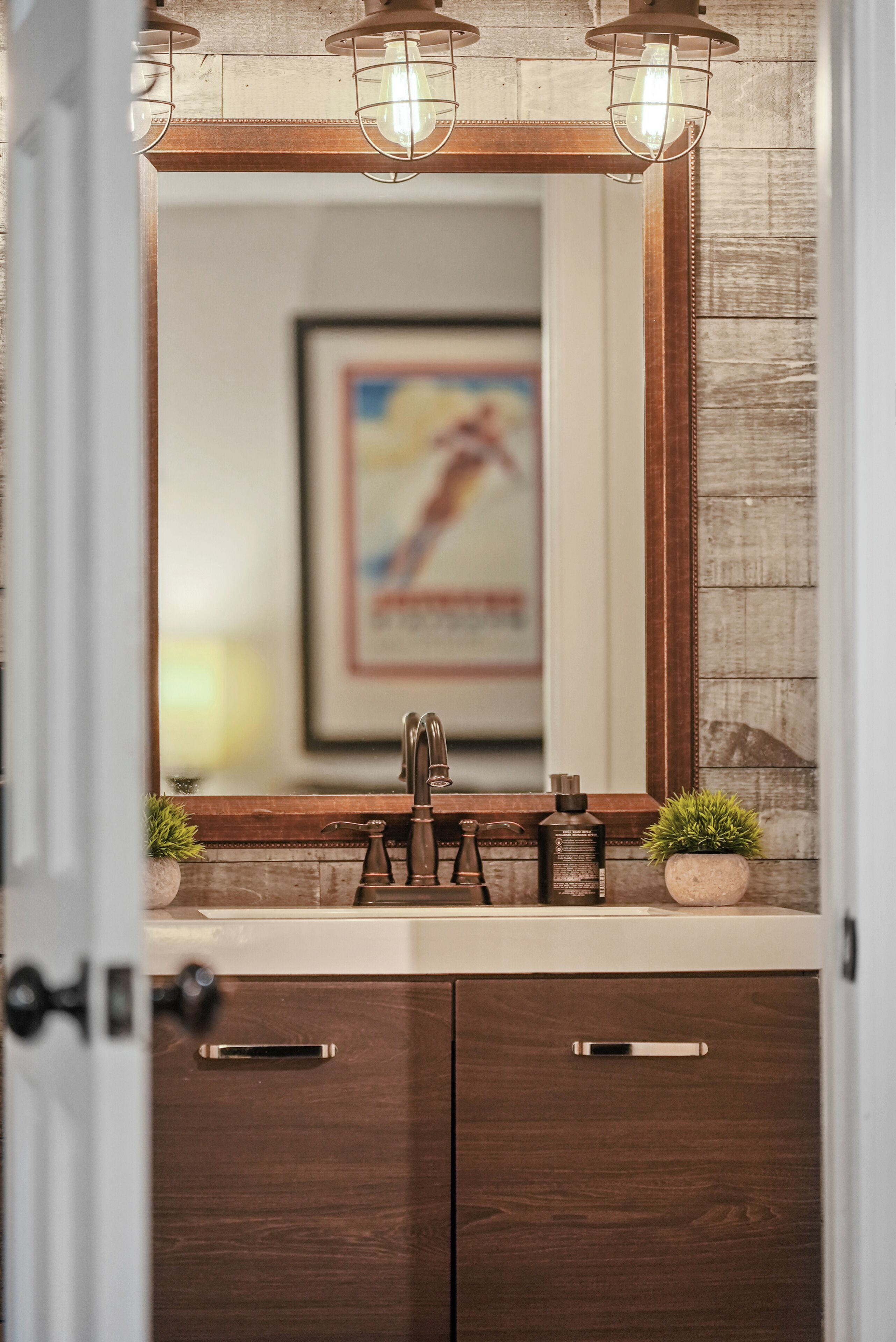 A bathroom with a wooden vanity, a mirror, and a framed picture on the wall.