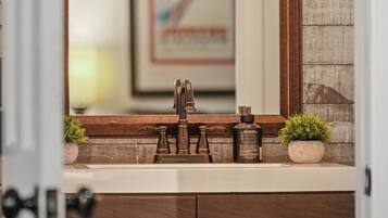 A bathroom with a wooden vanity, a mirror, and a framed picture on the wall.
