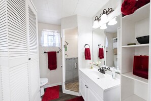 A bathroom with a white sink, a mirror, a shower, and a toilet. - Peaceful Farm Cabin for Couples | TX Hill Country (Georgetown)