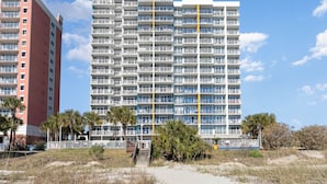 Ein mehrstöckiges Hotel mit Balkonen, einem Poolbereich und Blick auf den Strand.