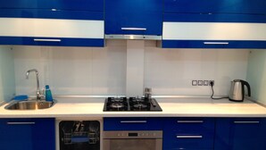 A modern kitchen with blue cabinets, a stainless steel sink, a gas stove, and a built-in oven.