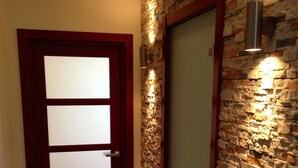 A hallway with a wooden door and a stone wall.