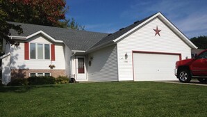 Ein eingeschossiges Haus mit Garage, davor ein roter Lastwagen und ein gepflegter Rasen.