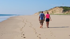 A couple walking on a sandy beach with footprints leading towards the ocean. - Ocean Cottage A/C near PB and Beachcomber. Steps to the beach! (Wellfleet)