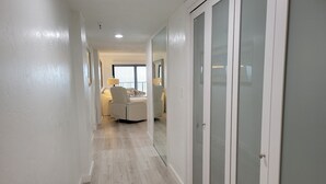 Un couloir avec un canapé, une lampe et une fenêtre équipée de stores.