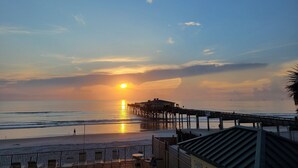 Une scène de plage avec une jetée qui s’avance dans l’océan au coucher du soleil.