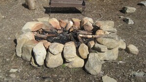 A fire pit surrounded by rocks with a bench nearby.