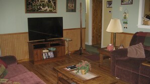 A living room with a television, wooden furniture, a couch, and a coffee table.