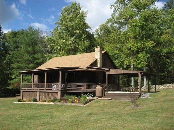 Relax on the covered porch amidst a serene landscaped garden and dense trees.