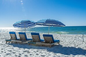 A beach with three striped umbrellas and wooden lounge chairs. - Relaxing Gulf Front Oasis, unit 332 (Pensacola)