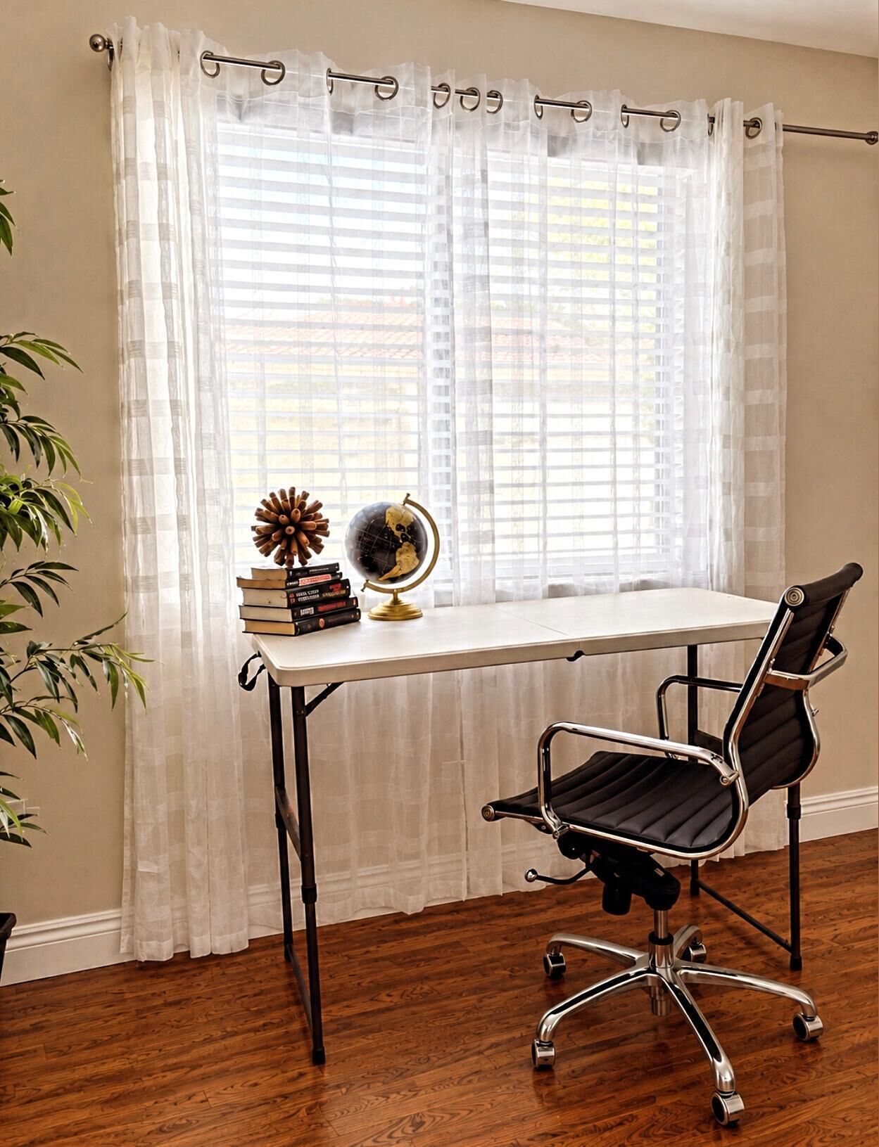 A room with a desk, chair, globe, books, and a plant.