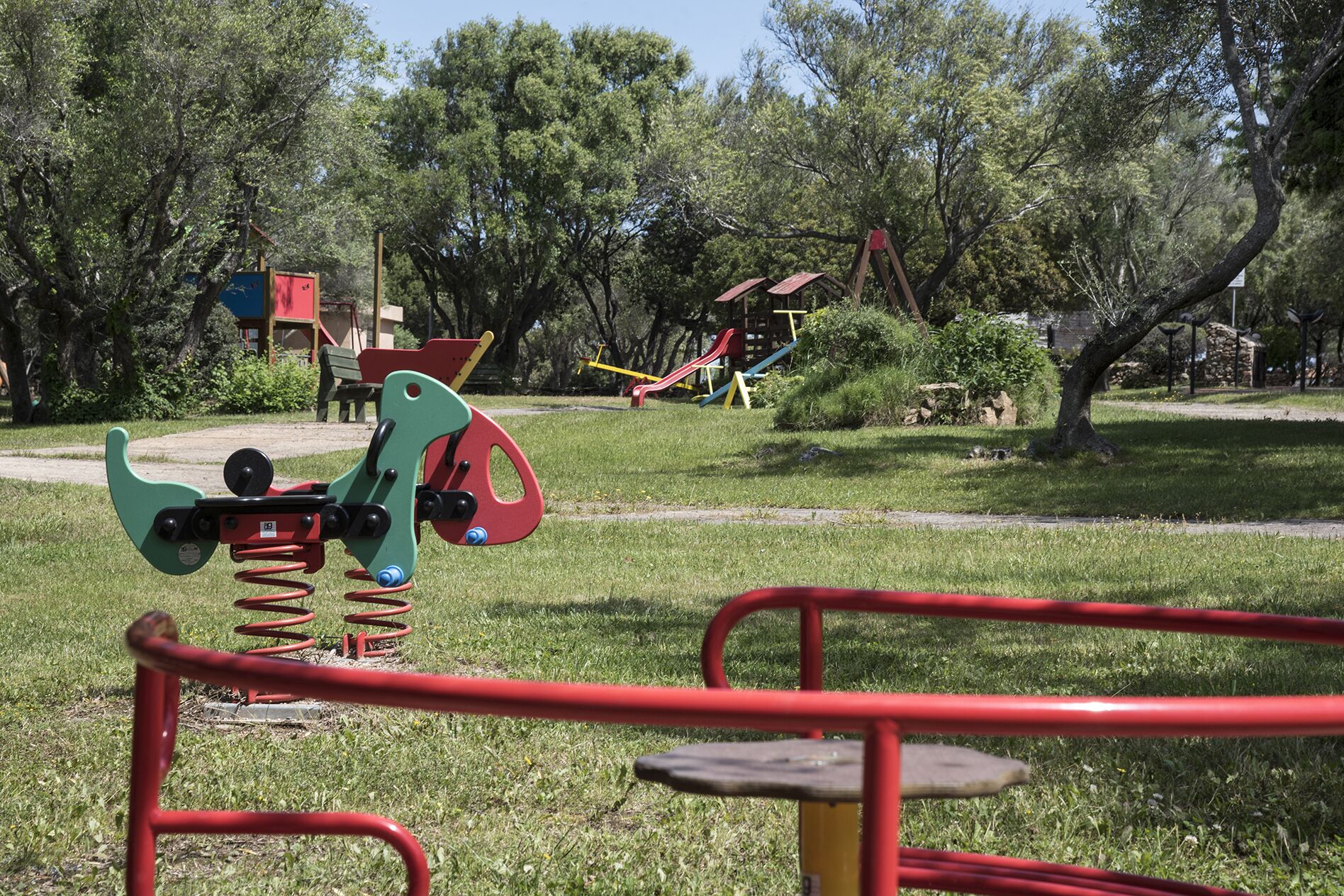A playground with various equipment including swings, slides, and a seesaw.